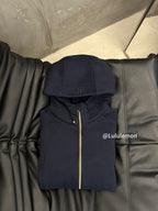 Navy zip-up hoodie with hood, small chest logo, and gold zipper trim