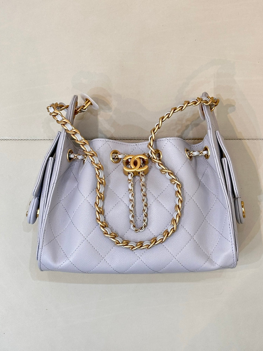 Light blue quilted handbag with gold chain handle, front flap, and Chanel logo medallion