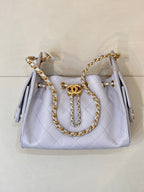 Light blue quilted handbag with gold chain handle, front flap, and Chanel logo medallion