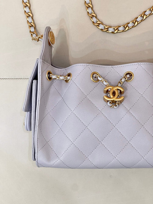 Light blue quilted handbag front with gold chain strap, rings, and Chanel logo charm