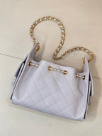 Light blue quilted handbag with gold chain handle and front metal ring closure details