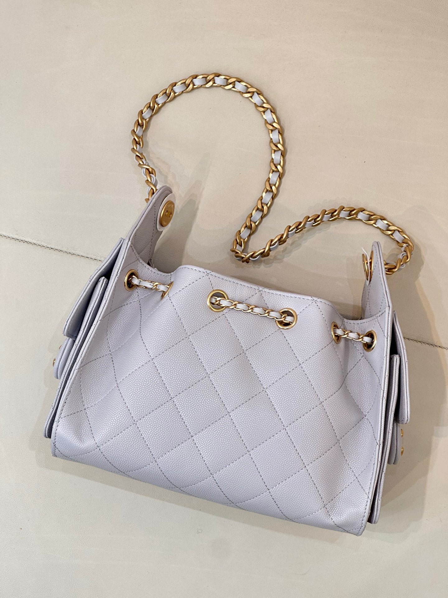 Light blue quilted handbag with gold chain handle and front metal ring closure details