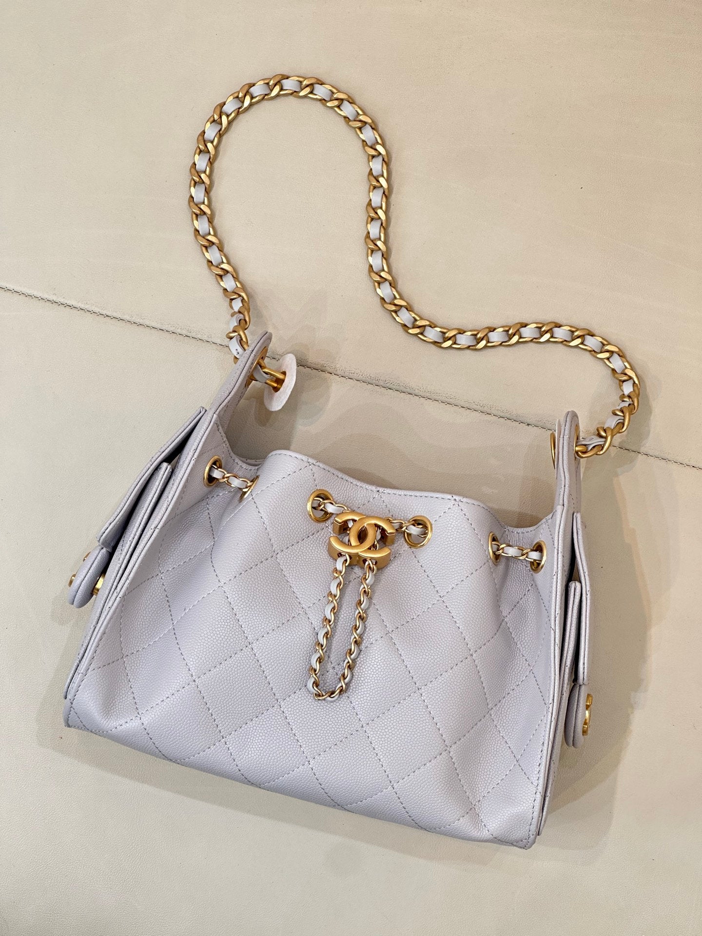 Light blue quilted handbag with gold chain shoulder strap and tassel-like side details