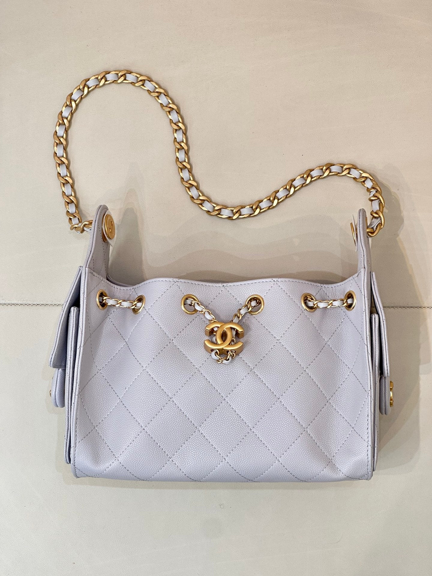 Light blue quilted handbag with gold chain shoulder strap and Chanel logo hardware