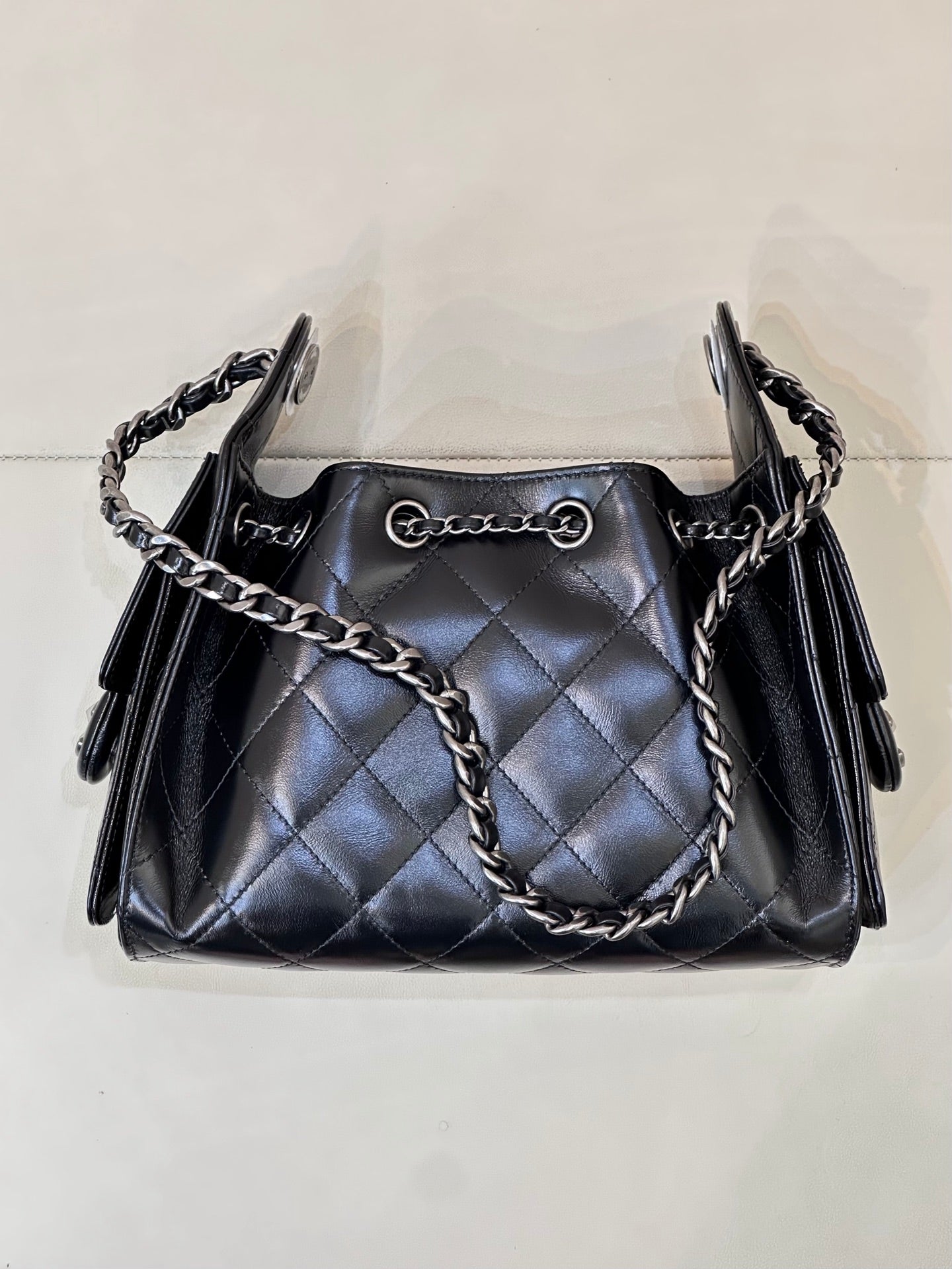 Chanel quilted black handbag front view with chain shoulder straps and tassel side details
