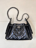 Chanel quilted black handbag with chain shoulder straps and top handle, metal closure hardware
