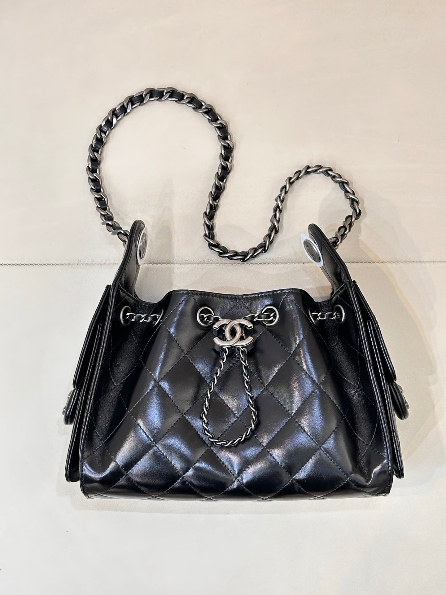 Chanel quilted black handbag with chain shoulder straps and top handle, metal closure hardware