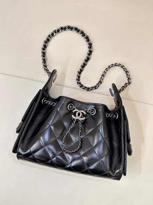Chanel quilted black handbag with chain shoulder straps, tassel details, and metal front clasp