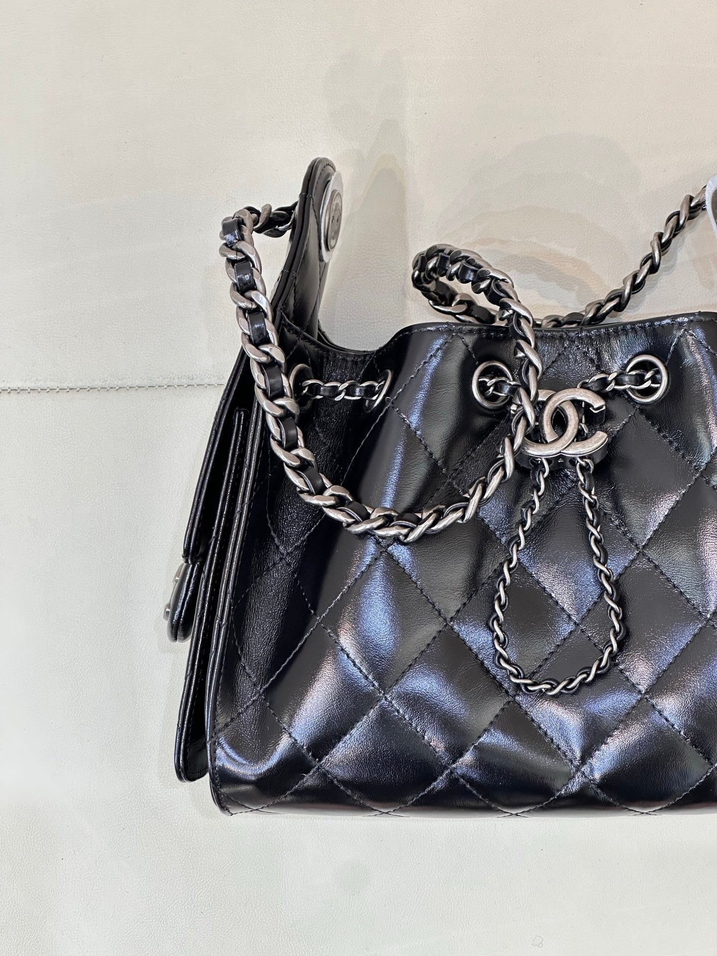 Chanel quilted black handbag corner view with chain strap and tassel side detailing