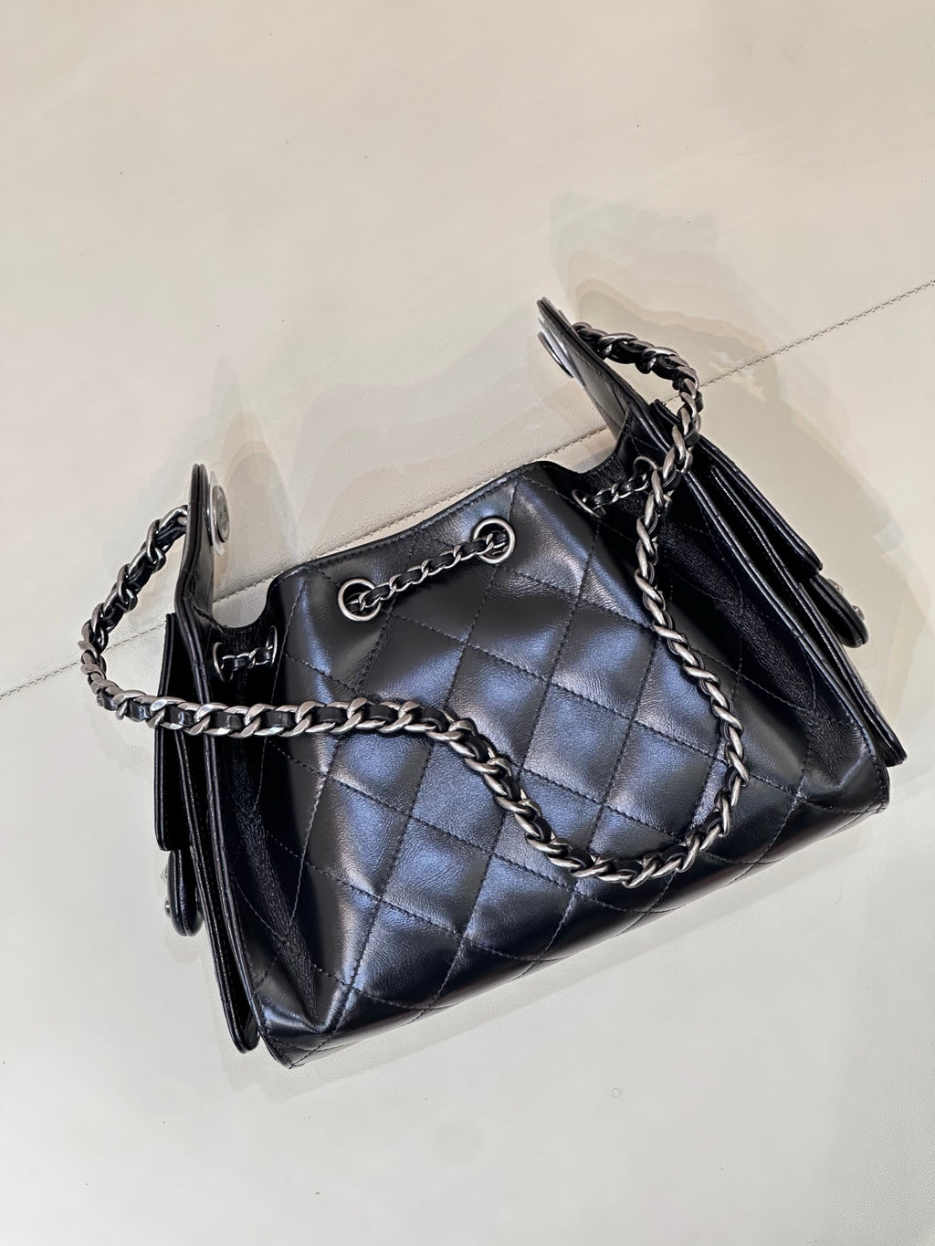Chanel quilted black handbag angled view with chain strap and front metal ring clasp