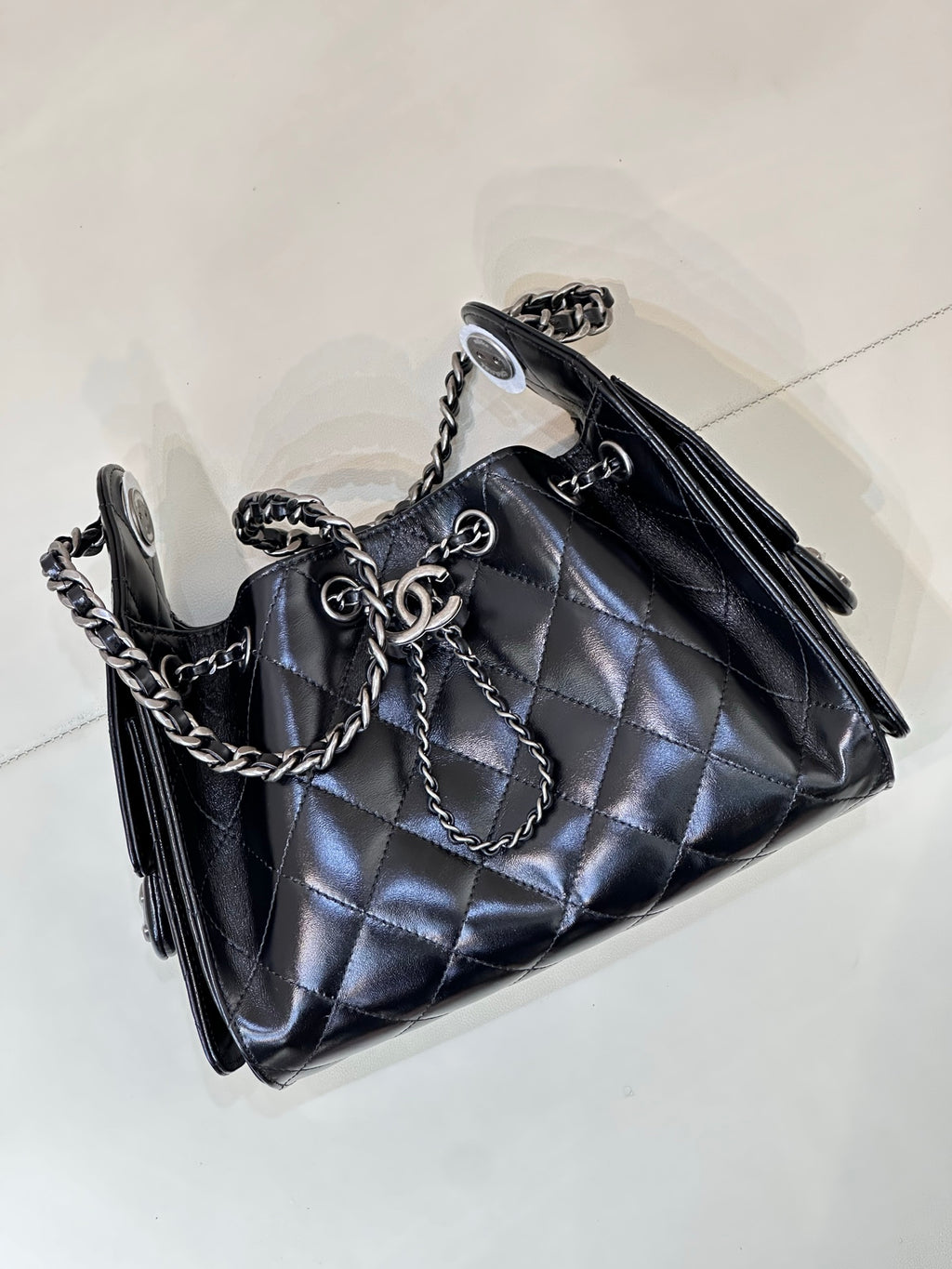 Chanel quilted black handbag angled view with chain shoulder straps and tassel accents