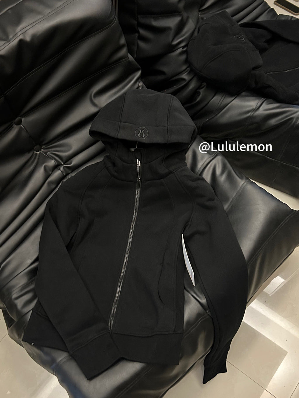 Black zip-up hoodie with hood and front zip, lying on surface