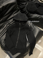 Black zip-up hoodie with hood and front zip, lying on surface