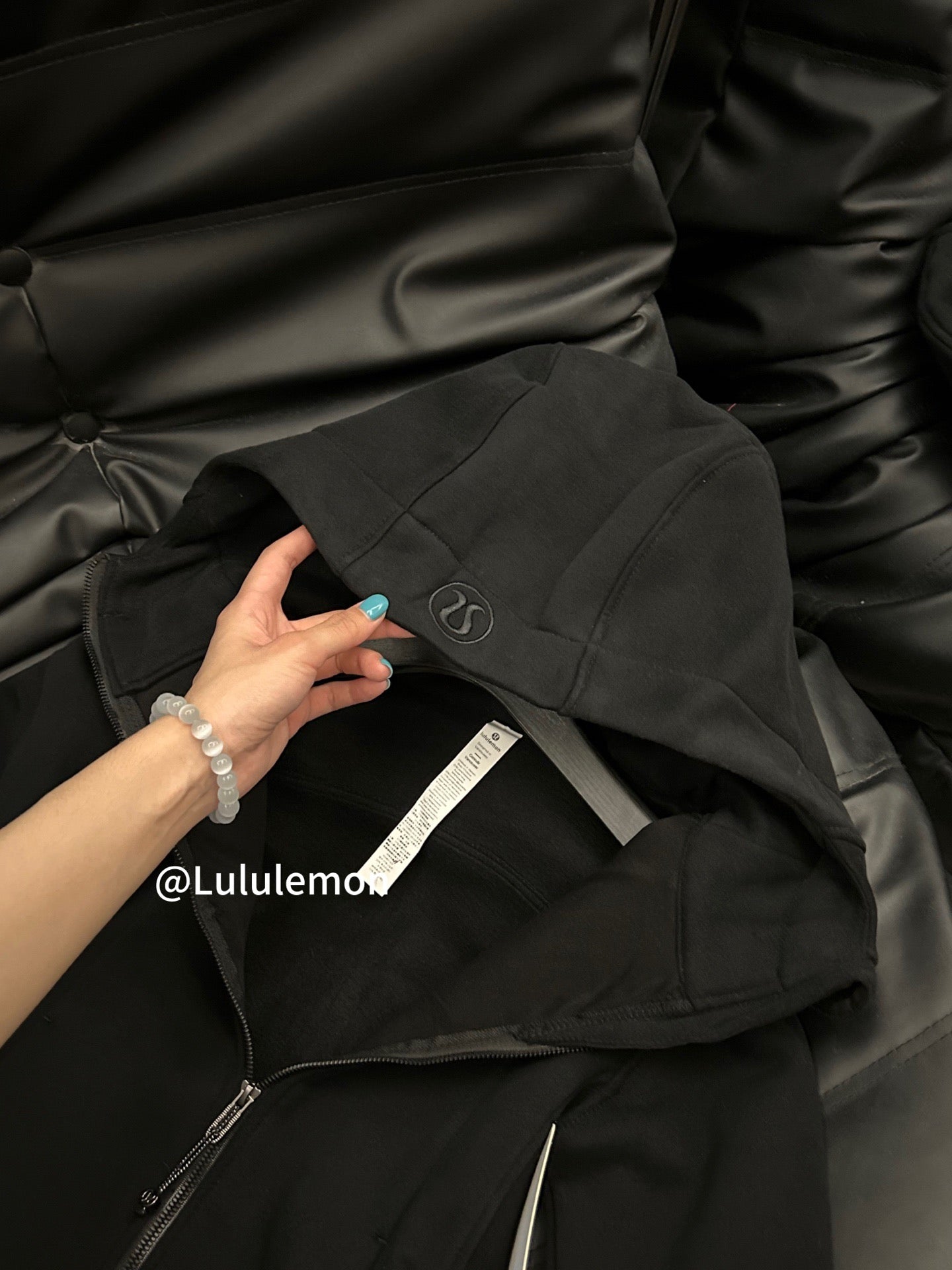 Black zip-up hoodie with hood and kangaroo pocket, detail view