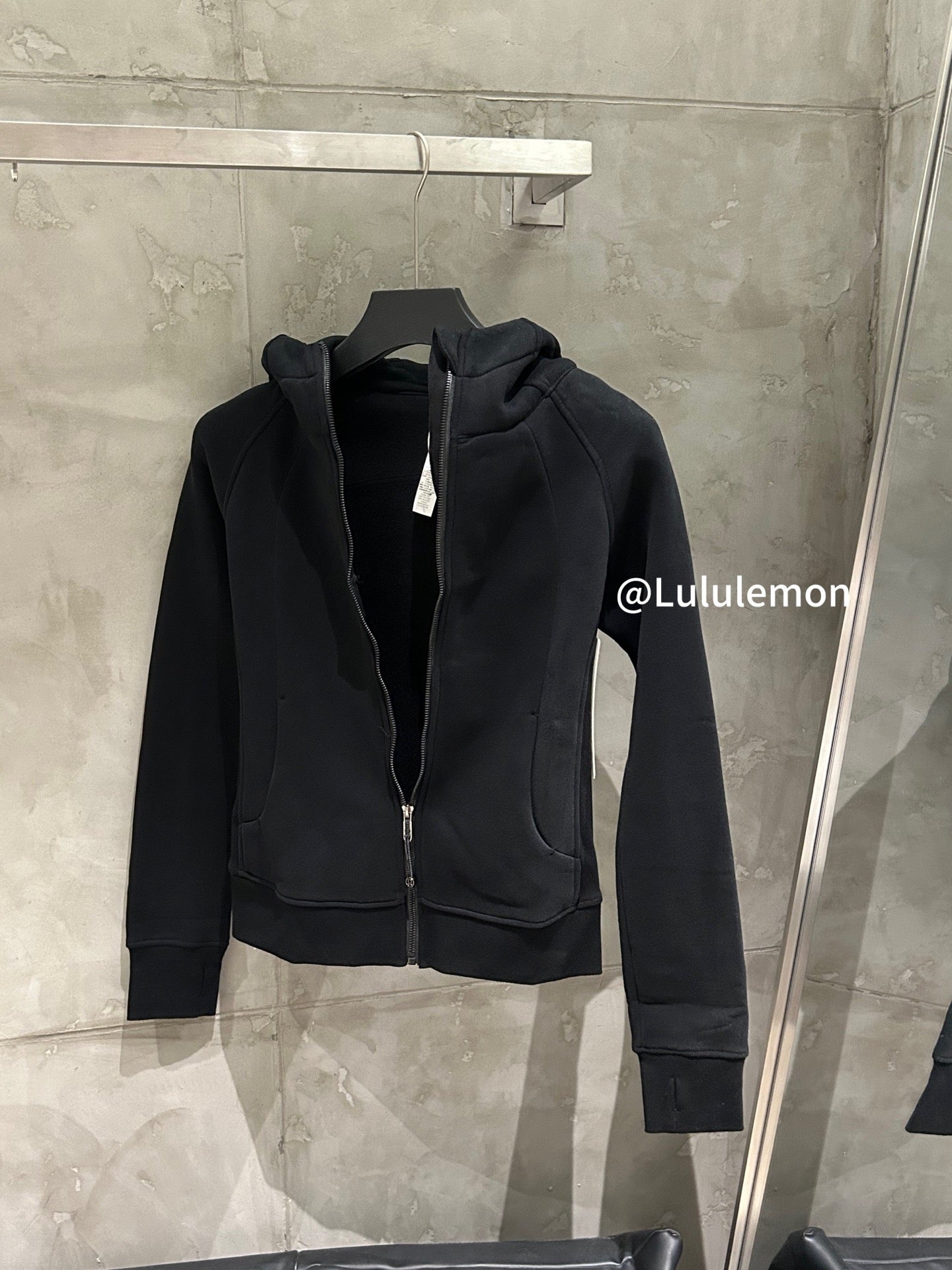 Black zip-up hoodie with hood and front pockets, hanging
