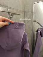 Lavender hooded jacket with circular logo patch on hood trim