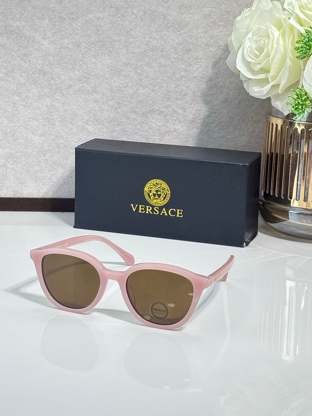 Versace sunglasses with pink frames and tinted lenses.