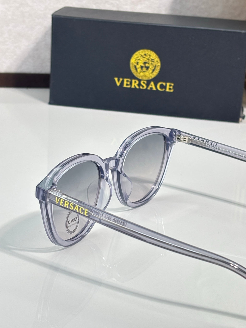 Versace sunglasses with clear frames and dark tinted lenses, close-up.