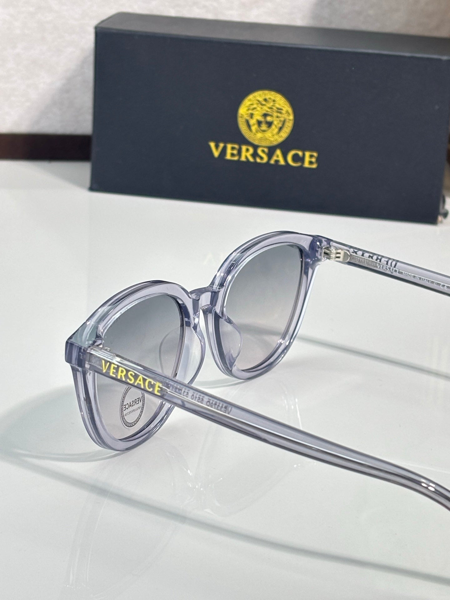 Versace sunglasses with clear frames and dark tinted lenses, close-up.