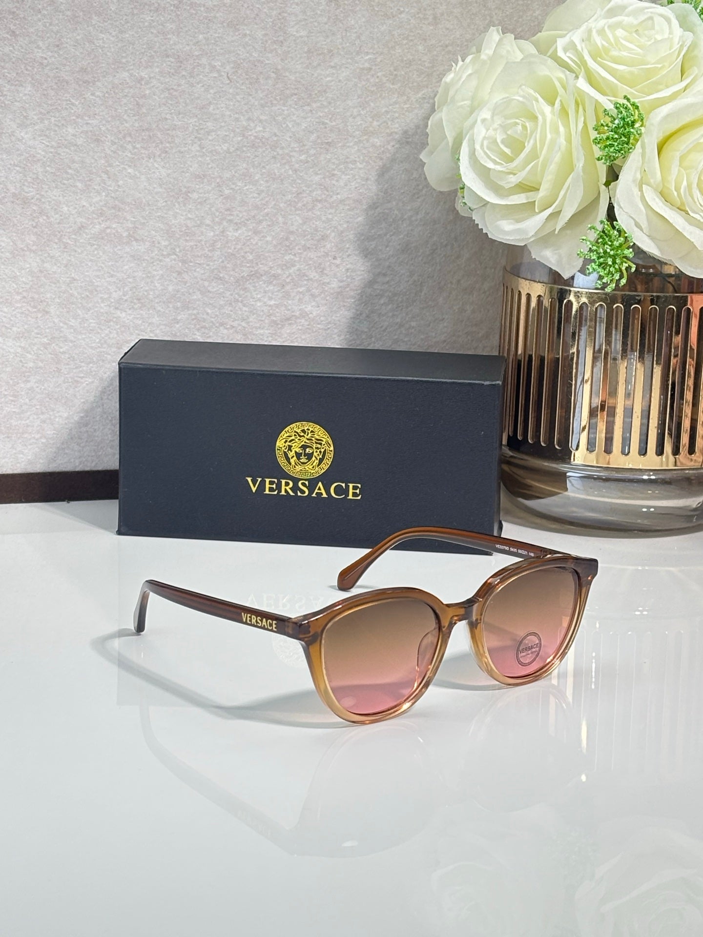 Versace sunglasses with brown frames and rose-tinted lenses.