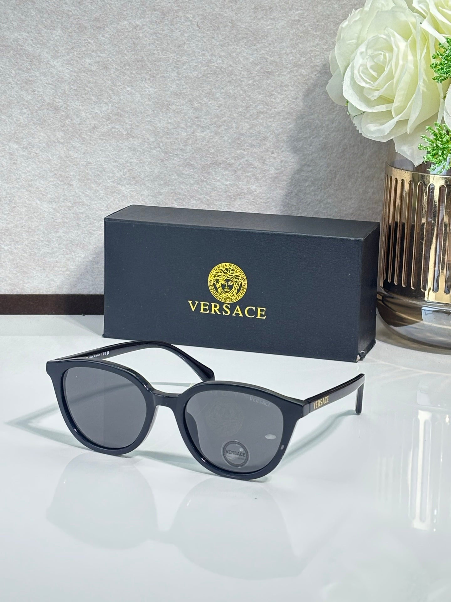 Versace sunglasses with black frames and dark tinted lenses, side view.