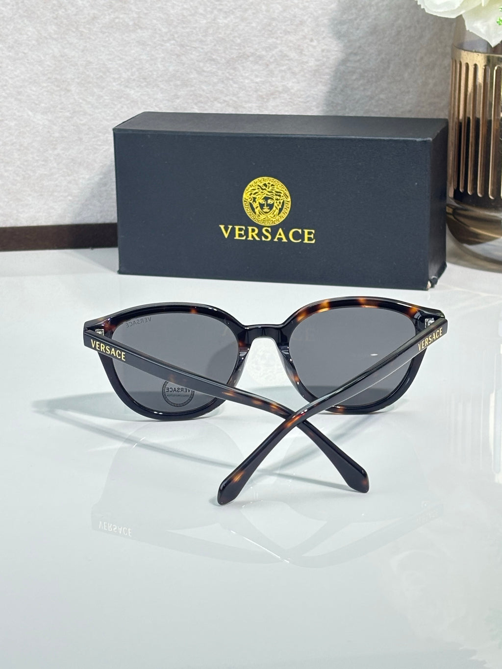Versace sunglasses with dark lenses and tortoise-accented temples, angled.