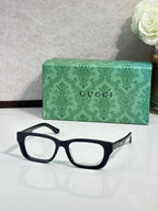Gucci eyeglasses with black frames and clear lenses; green logo case.