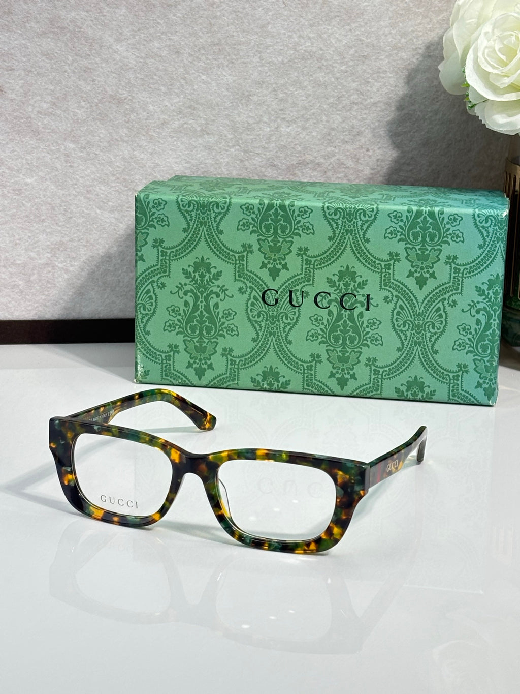 Gucci eyeglasses with tortoiseshell frames and clear lenses; green logo case.