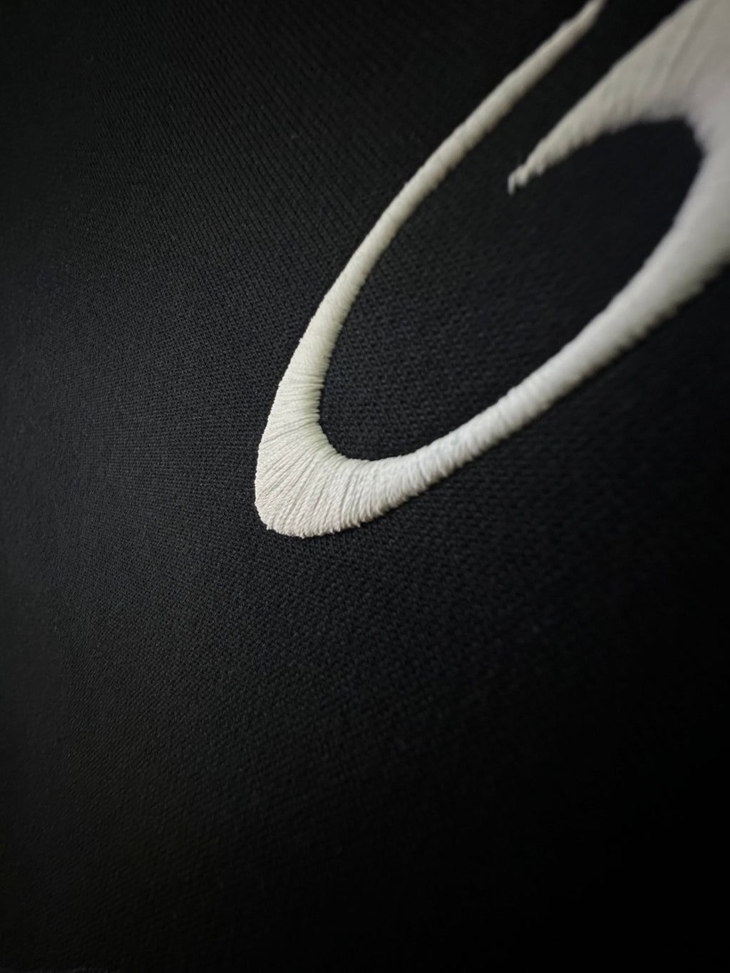 Balenciaga shorts close-up with white curved logo detail on dark fabric