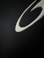 Balenciaga shorts close-up with white curved logo detail on dark fabric