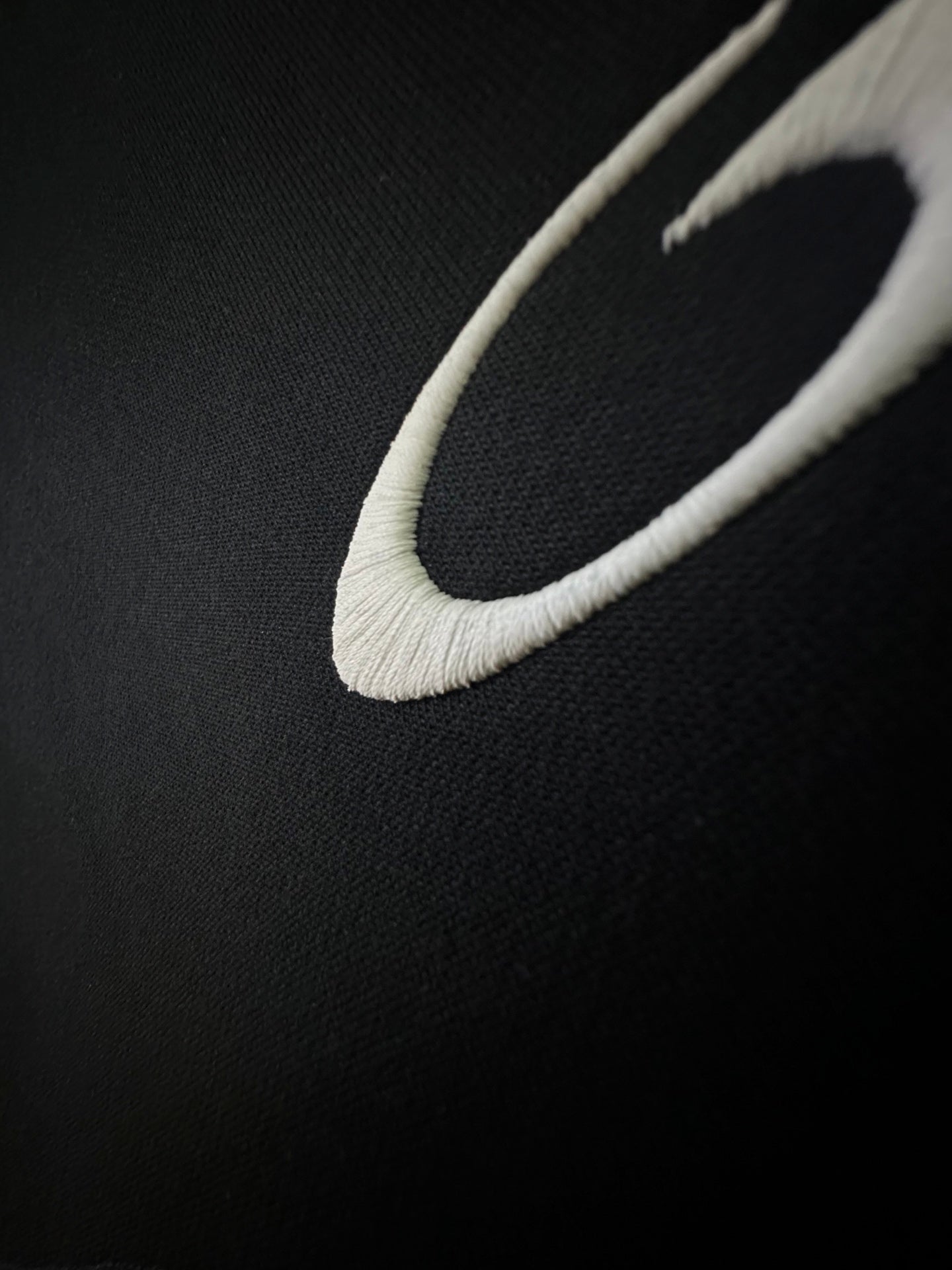 Balenciaga shorts close-up with white curved logo detail on dark fabric