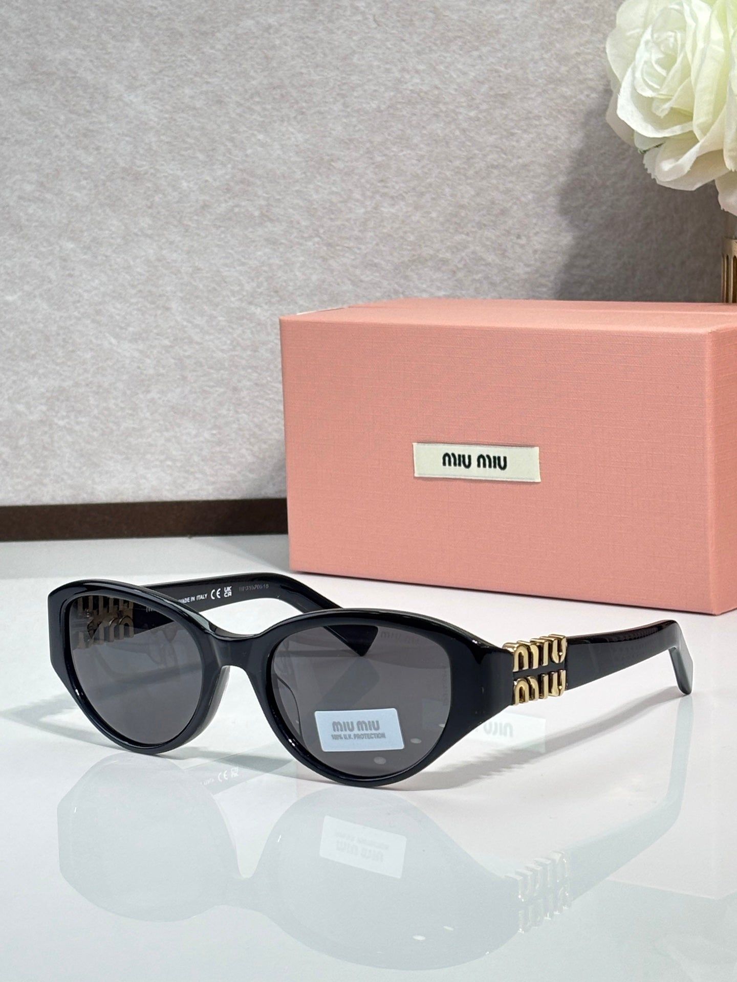 Black cat-eye sunglasses with dark lenses and gold-tone logo arms