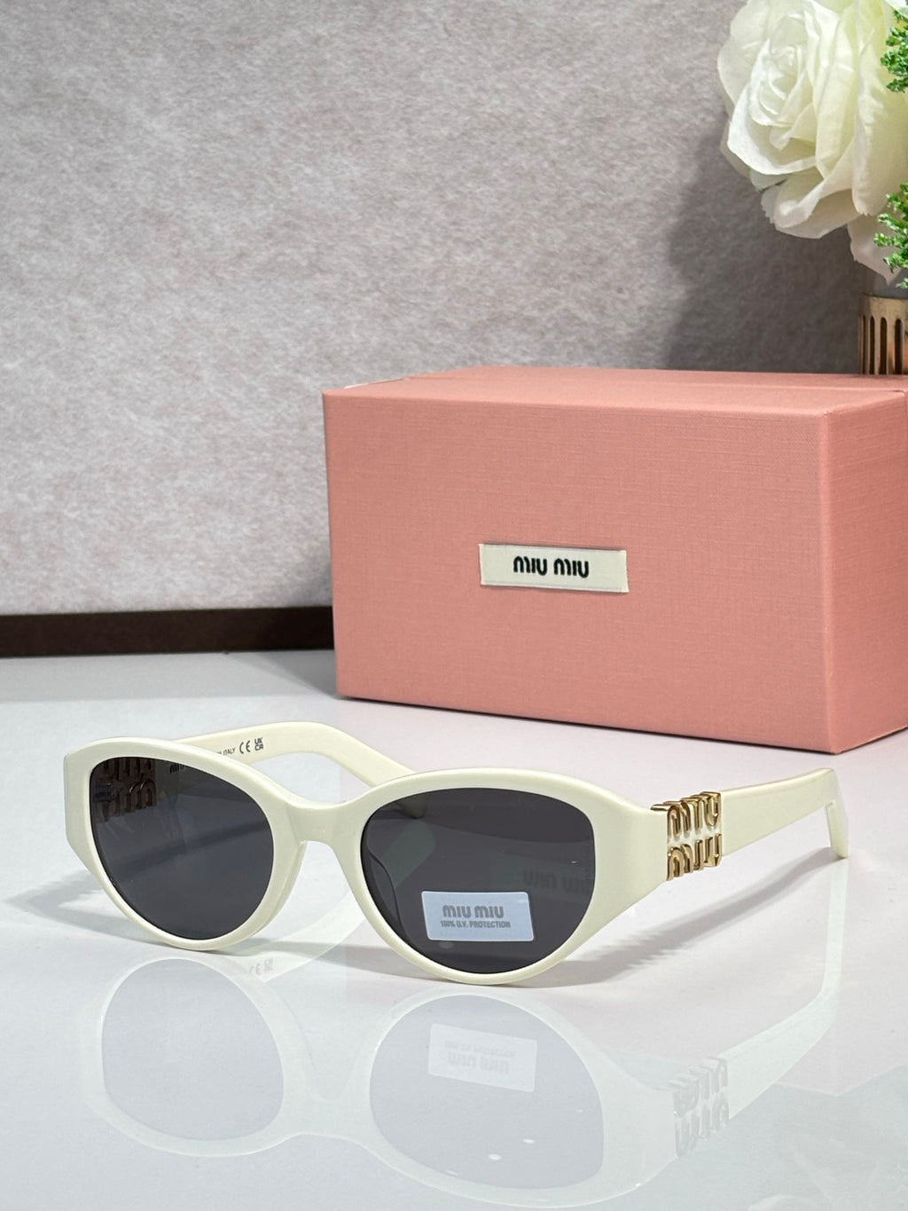Cream cat-eye sunglasses with dark lenses and gold-tone logo temples