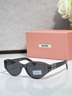 Black cat-eye sunglasses with dark lenses and logo badge on the lens