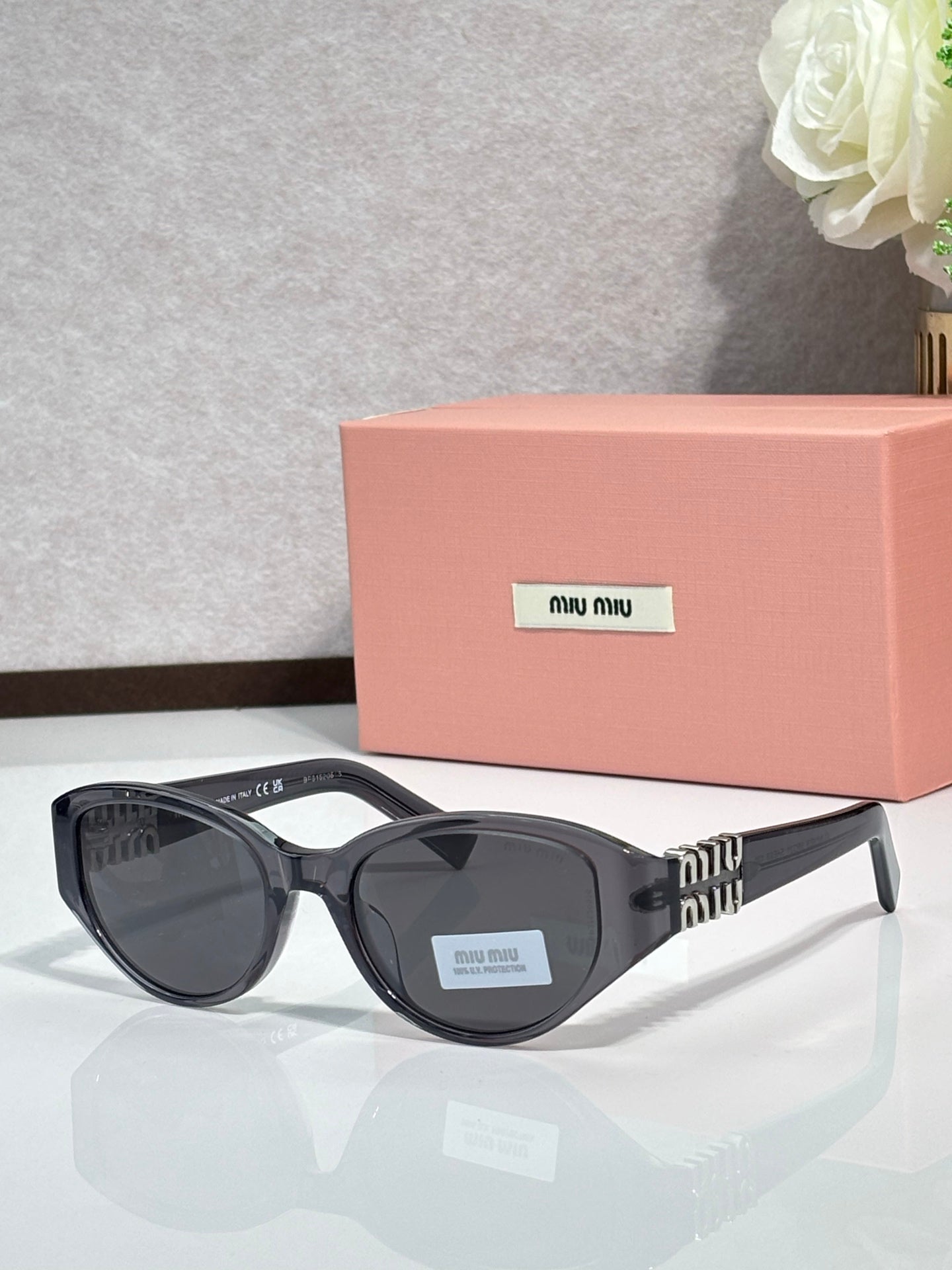 Black cat-eye sunglasses with dark lenses and logo badge on the lens