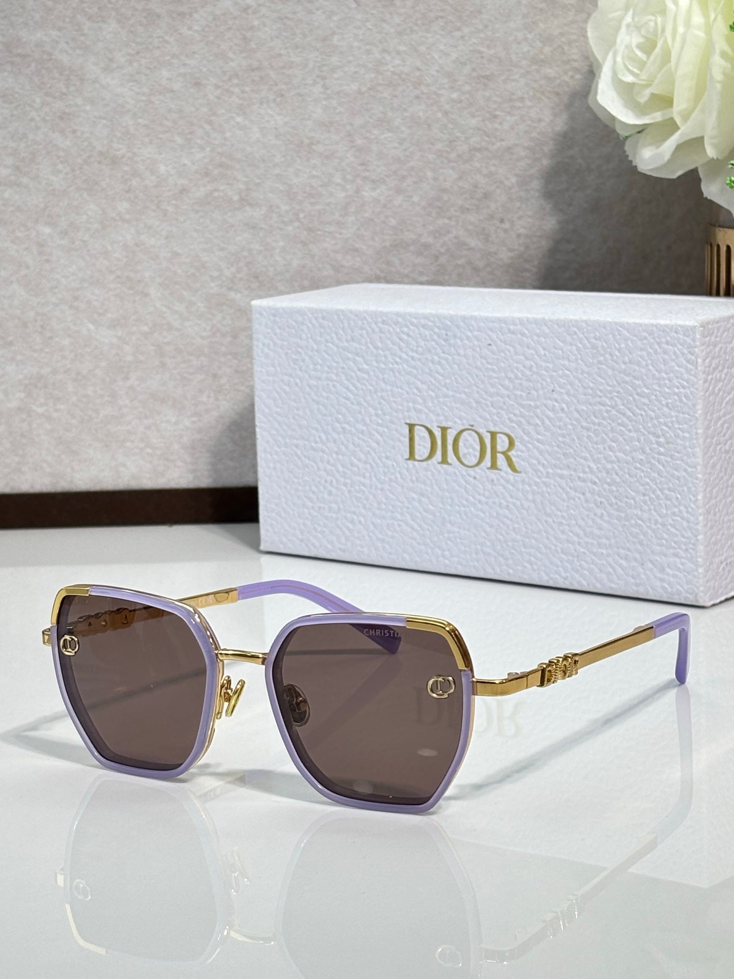 Dior sunglasses with purple-tinted lenses and gold-tone oversized square frames