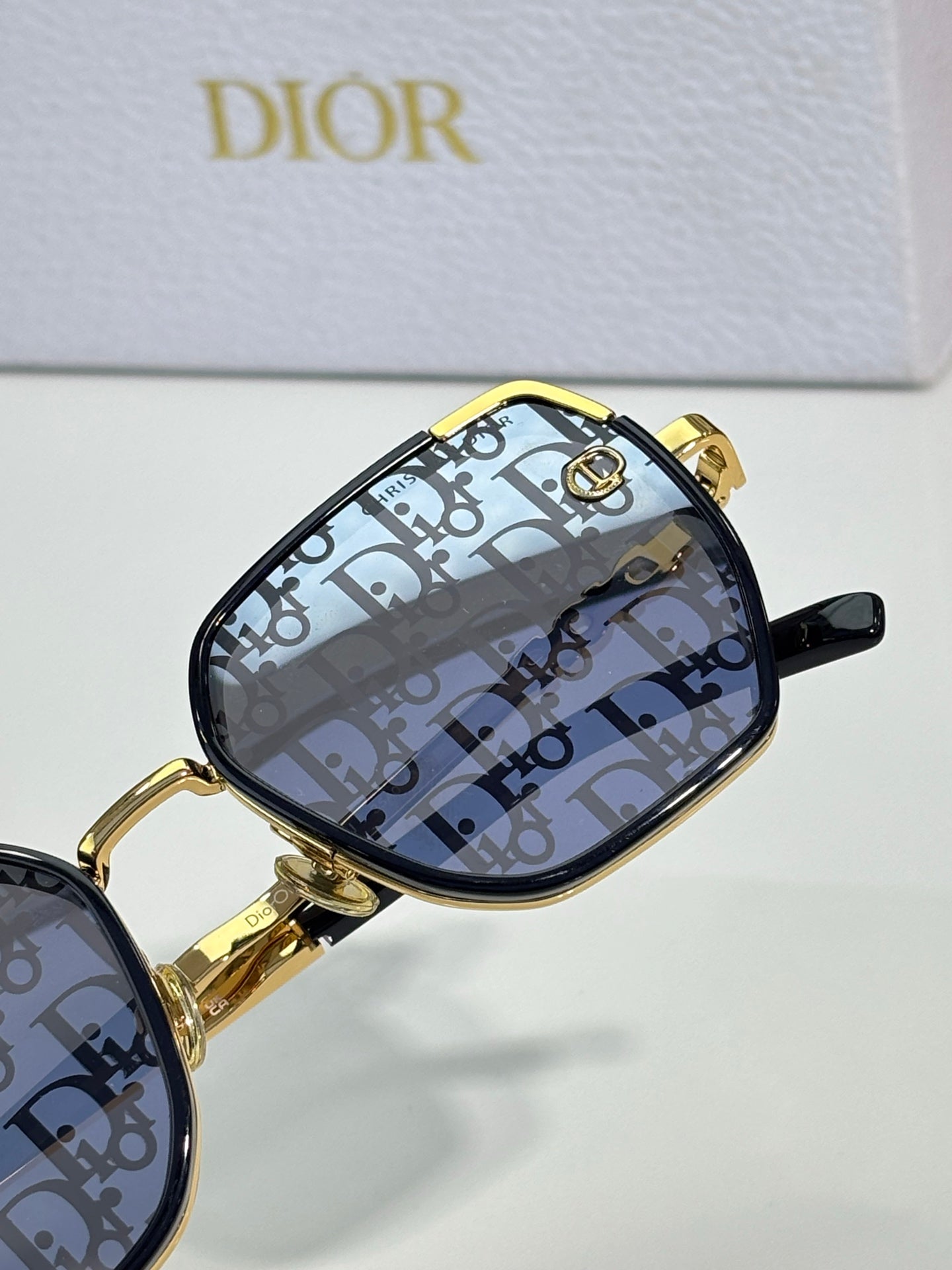 Dior sunglasses with black lenses and gold-tone frames featuring logo pattern