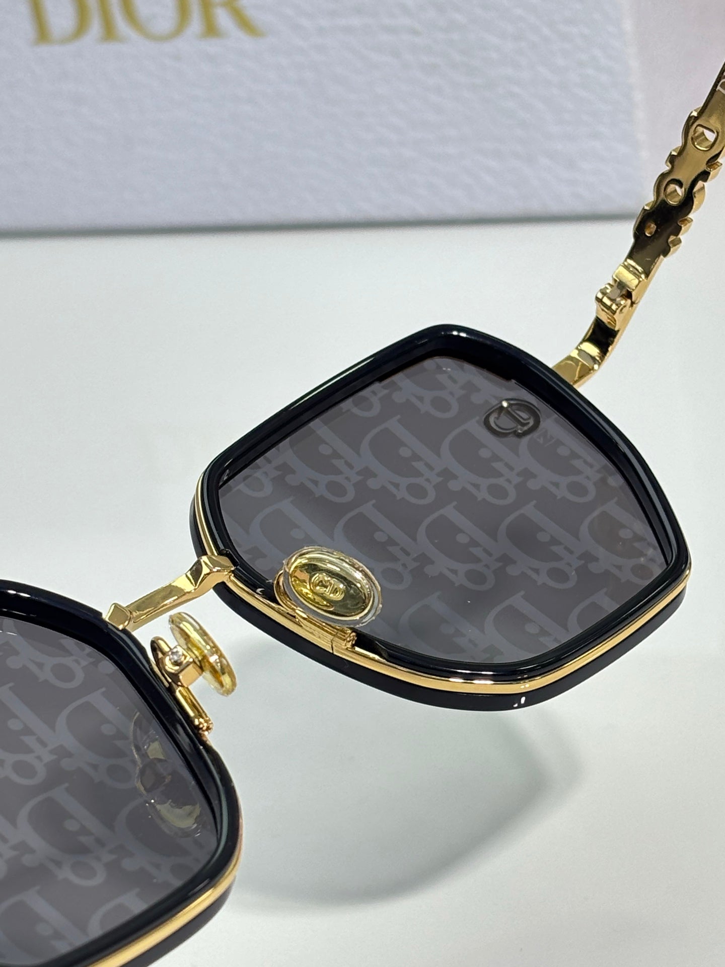 Dior sunglasses close-up with logo-pattern lenses and gold-tone frame details