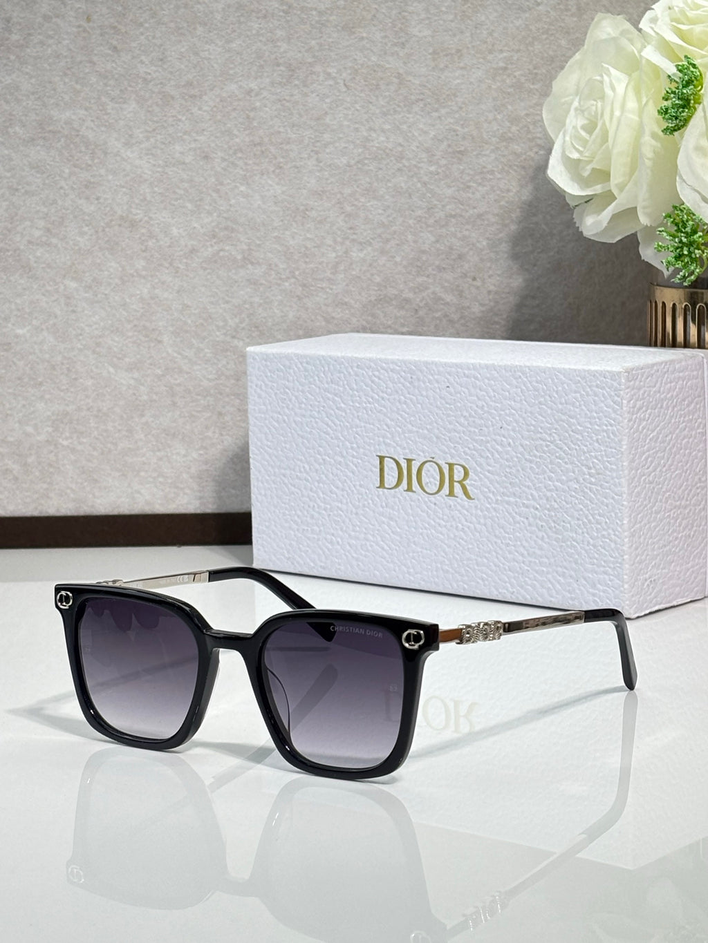 Sunglasses by Dior with black frames, dark lenses, and gold bridge accent