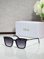 Sunglasses by Dior with black frames, dark lenses, and gold bridge accent
