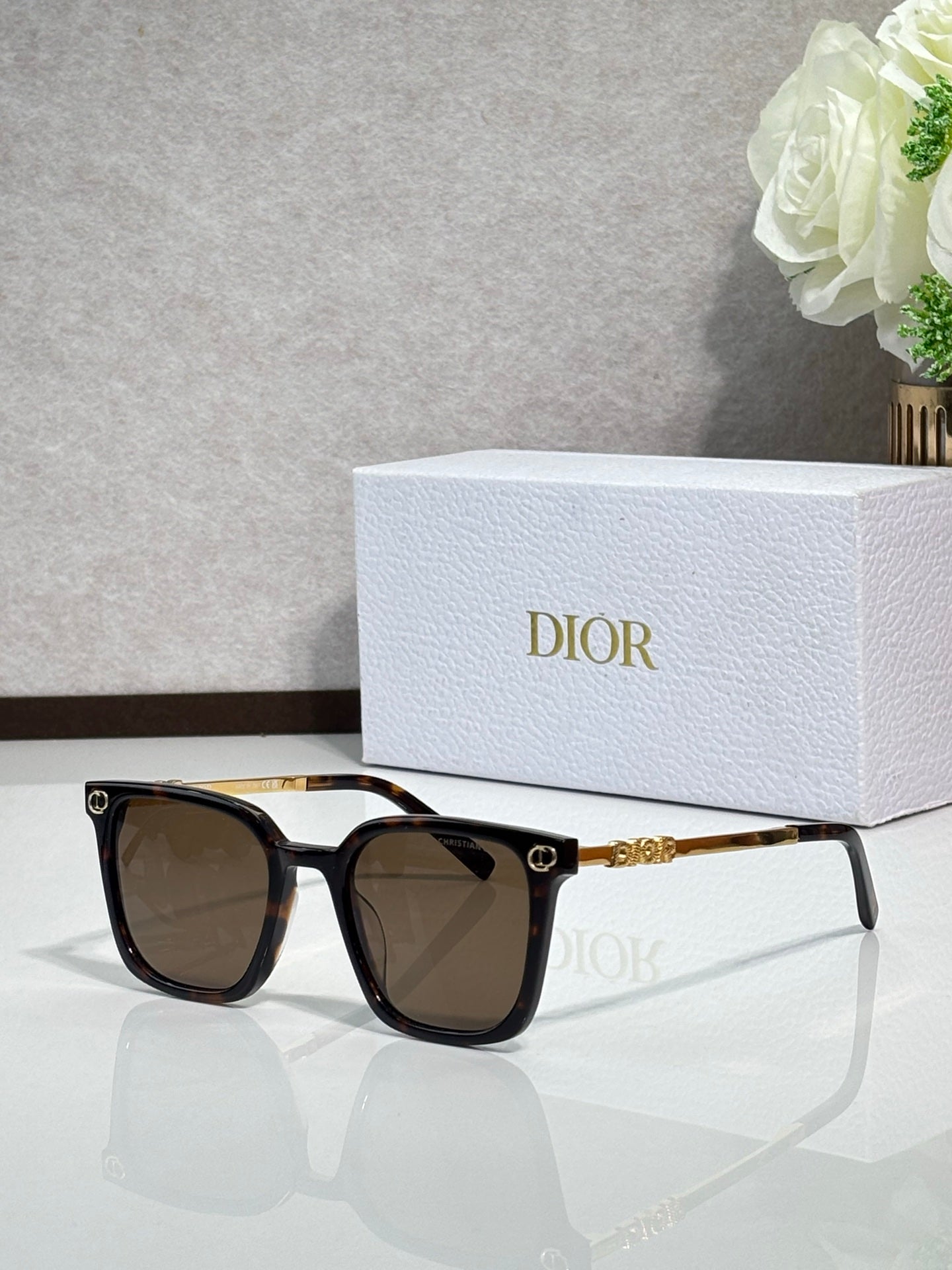 Sunglasses by Dior with black frames, brown-tinted lenses, and gold detailing