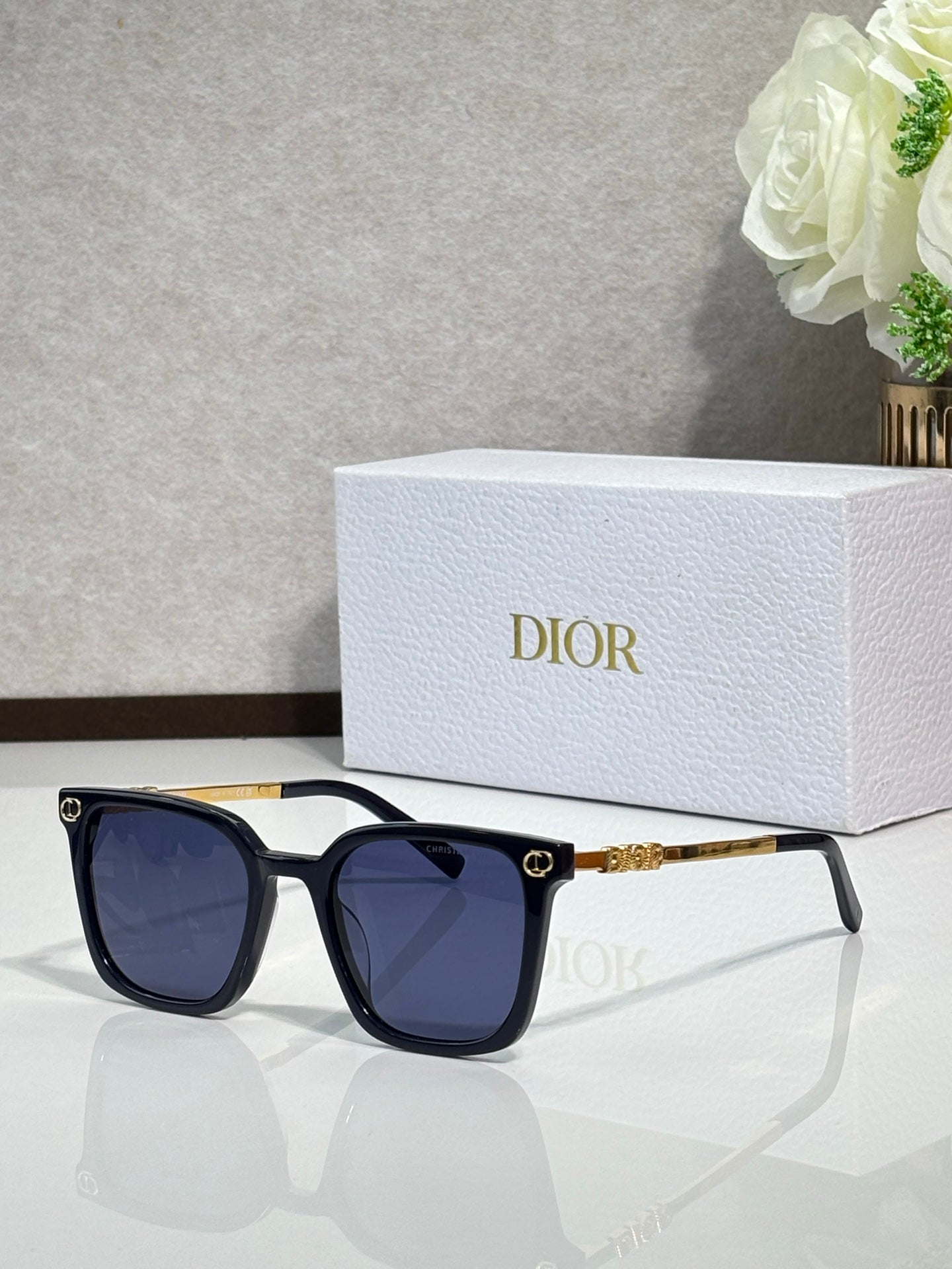 Sunglasses by Dior with dark frames, dark lenses, and gold temple accents