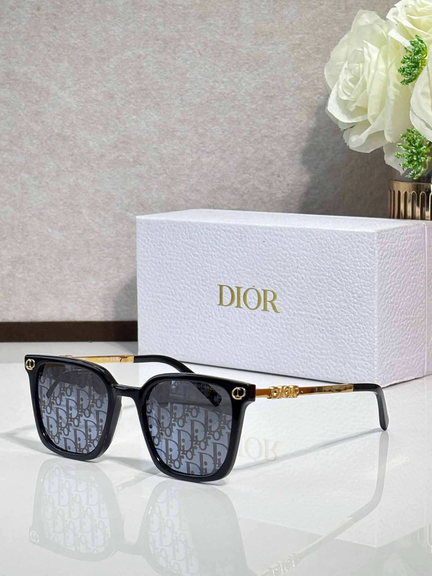 Sunglasses by Dior with black frames, patterned lenses, and gold temple details