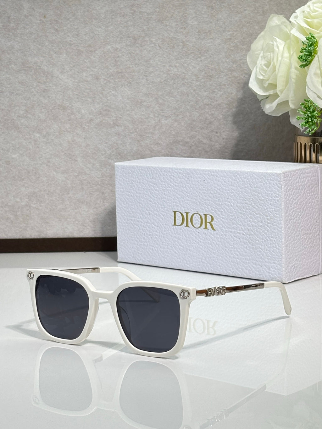 Sunglasses by Dior with white frames and dark lenses, with gold temple accents
