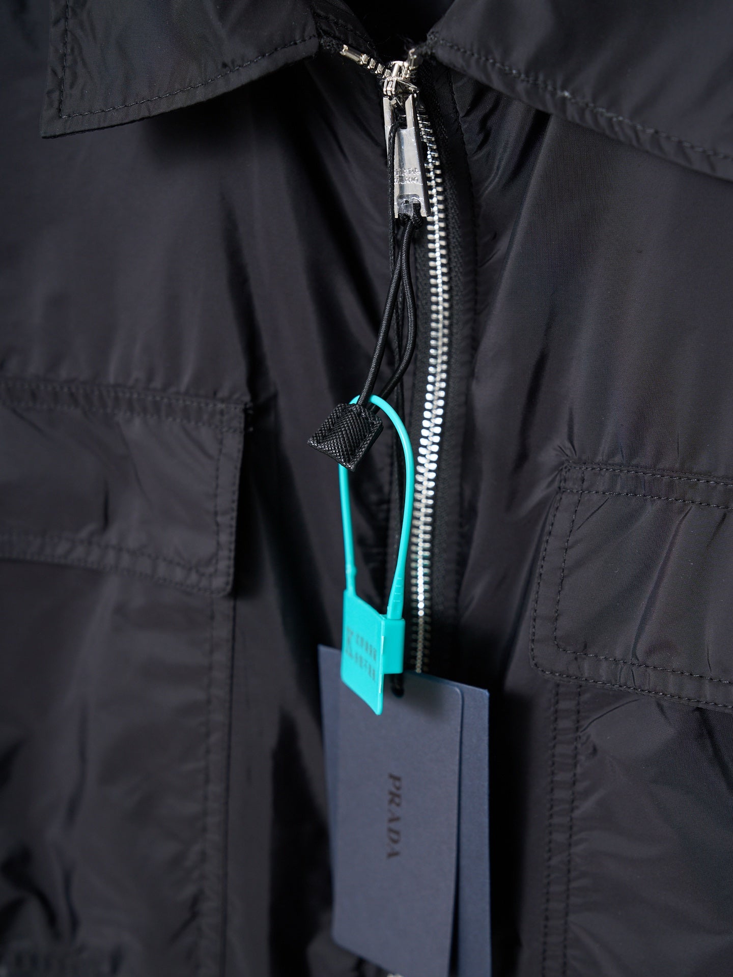 Prada dark jacket close-up of front zipper and pocket trim