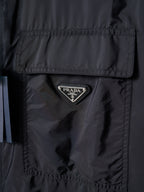 Prada dark jacket close-up of triangular Prada logo patch