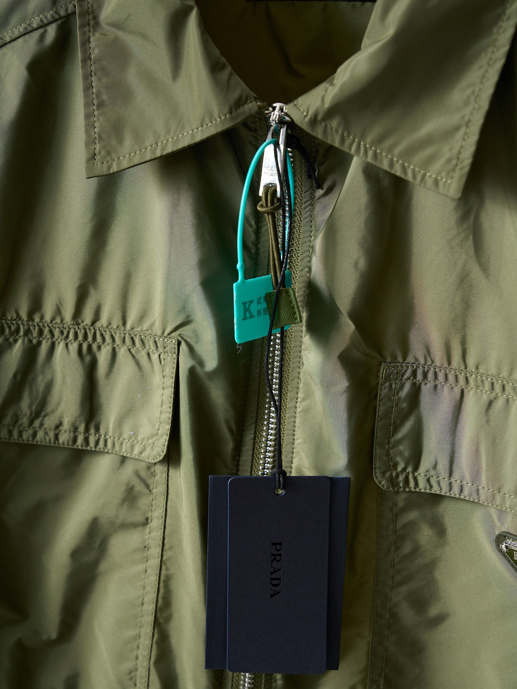 Olive green Prada jacket front zipper with hanging tags and metal pull