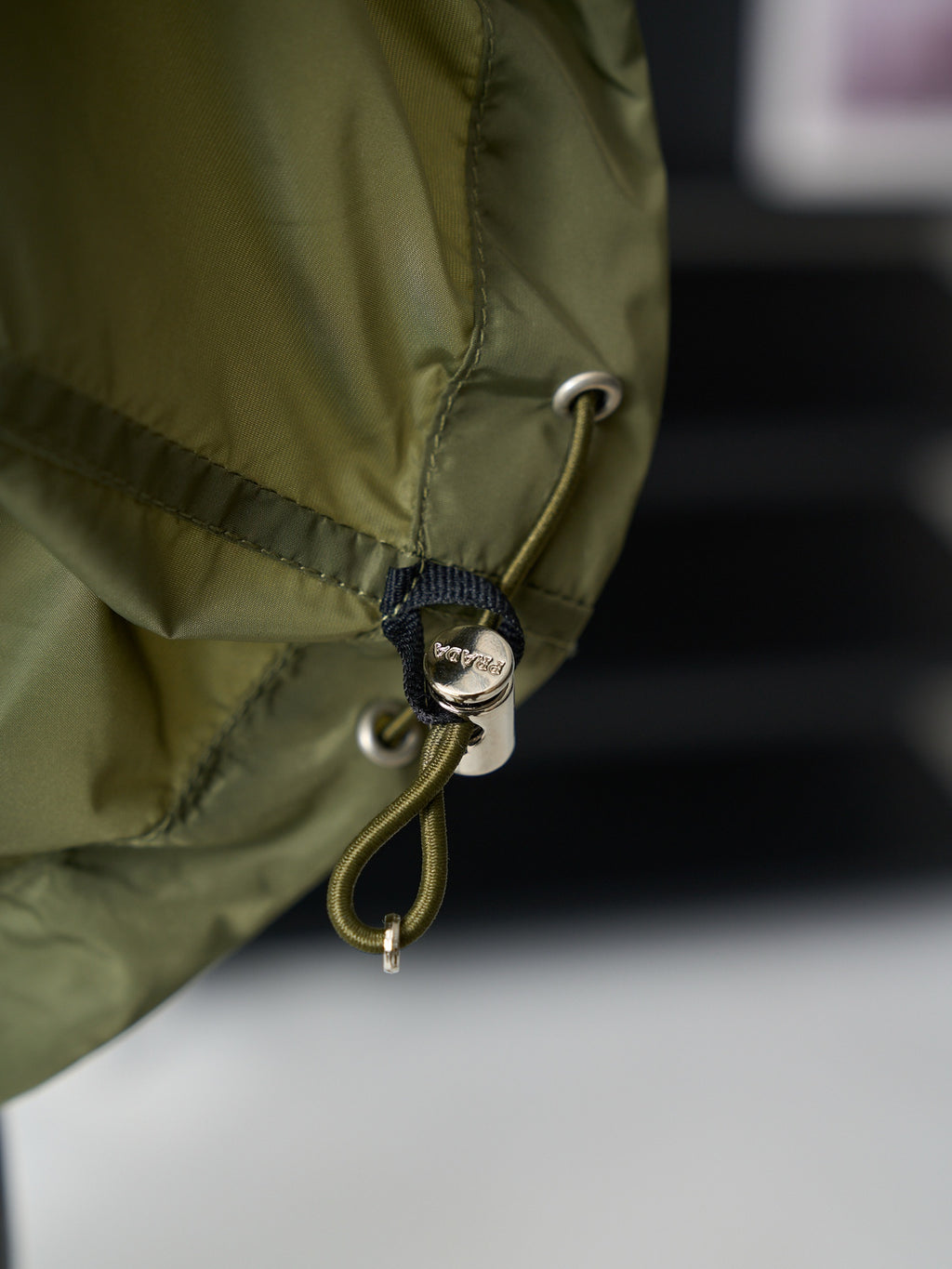 Olive green Prada jacket hem drawcord with metal eyelet and round charm
