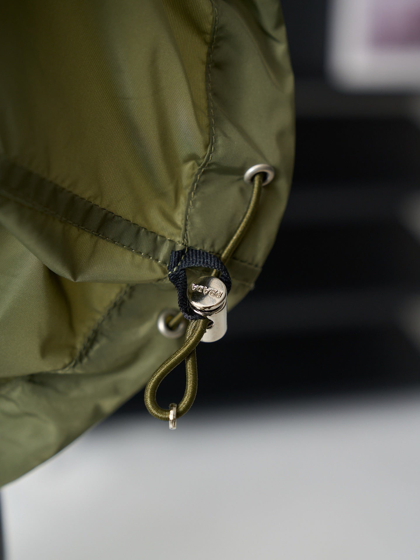 Olive green Prada jacket hem drawcord with metal eyelet and round charm