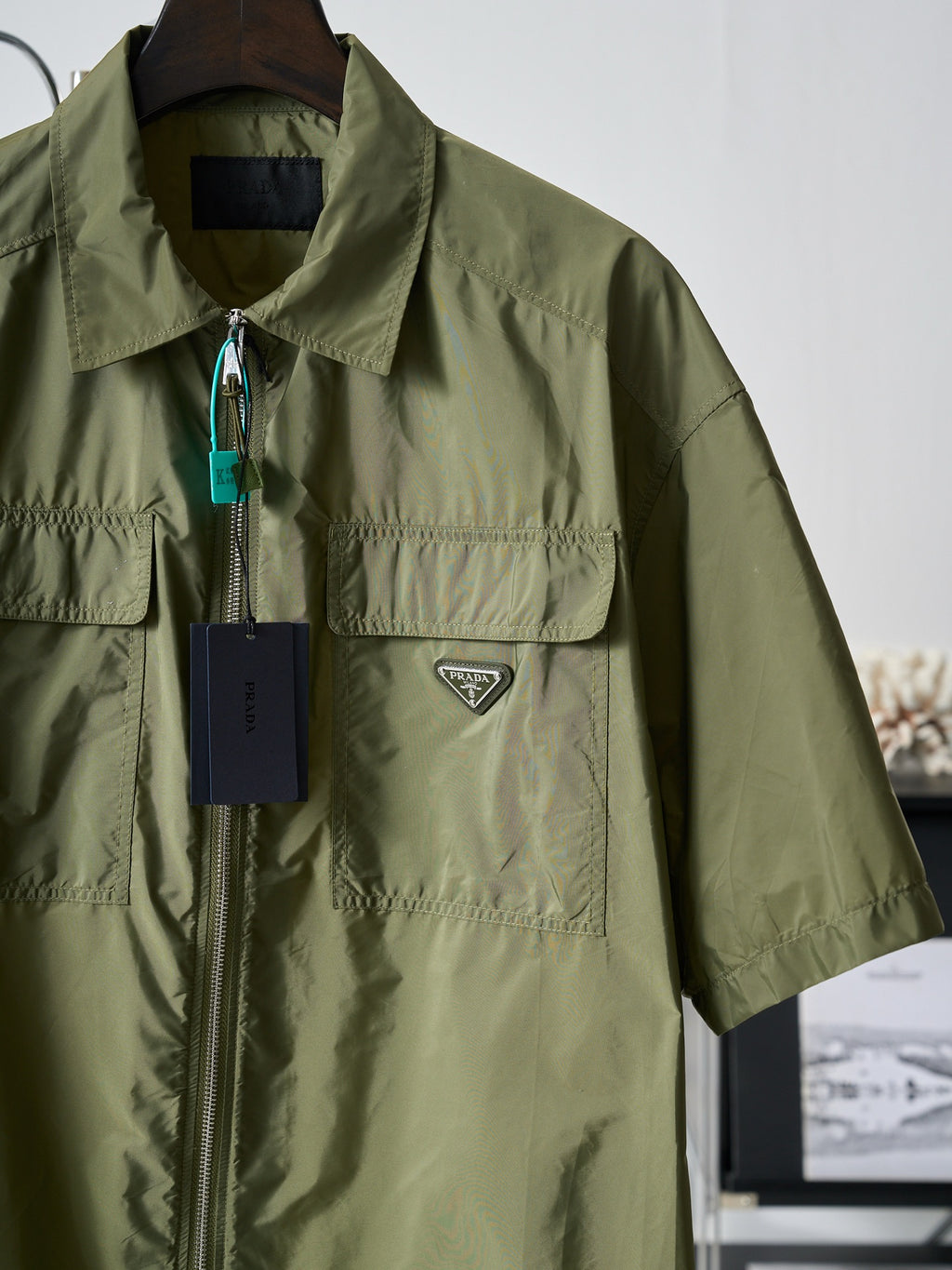 Olive green Prada short-sleeve jacket with stand collar, zip front, and logo patch